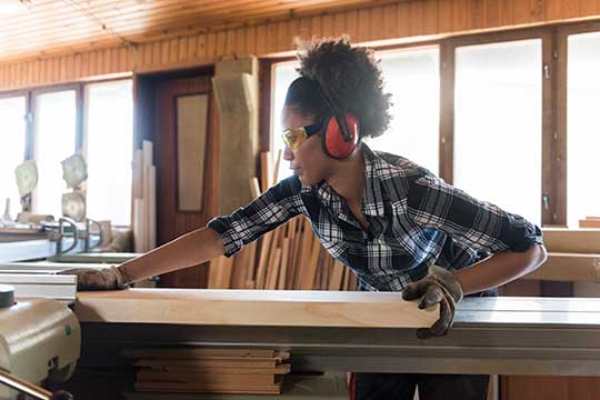 Woman wearing ear protection while she works with a saw