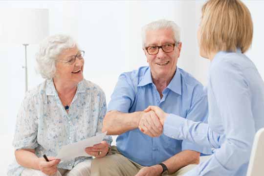Elderly couple shaking hands with hearing professional